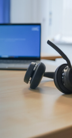 Headset lying on a desk with a computer in the background